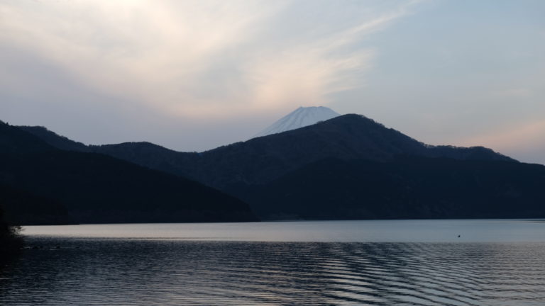 The sun sets over Hakone as the mountain range and water begin to draken