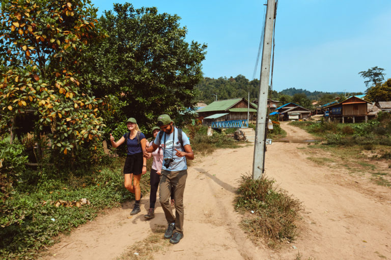 3 Backpackers hiking through village